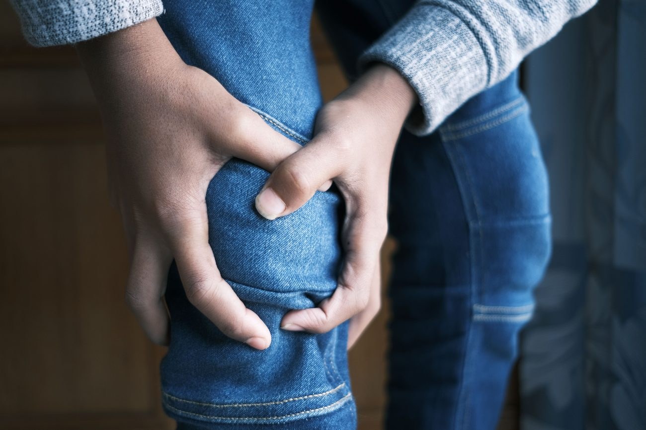 Person holding their knee, indicating knee pain